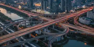 Modern highway interchange with high-speed trains and city skyline at dusk, representing advanced infrastructure.